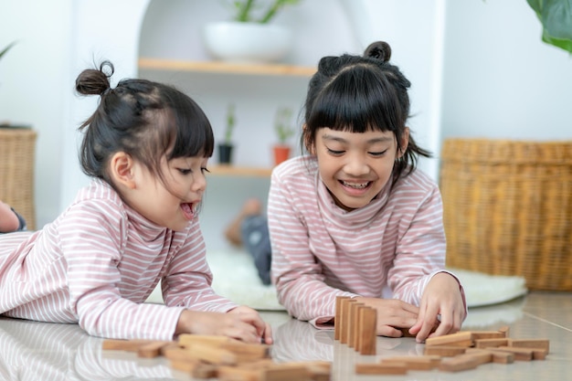 家で木製のスタックを再生するアジアの兄弟の女の子