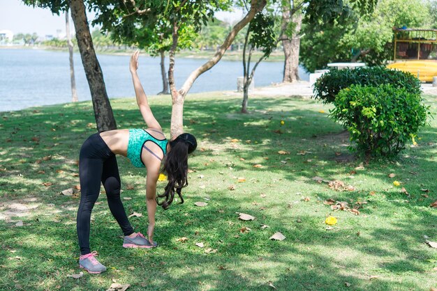 아시아의 날씬한 여성이 일하기 전에 워밍업을 하고 태국 사람들을 위한 날씬한 운동을 조깅하기 전에 몸을 쭉쭉 뻗는다
