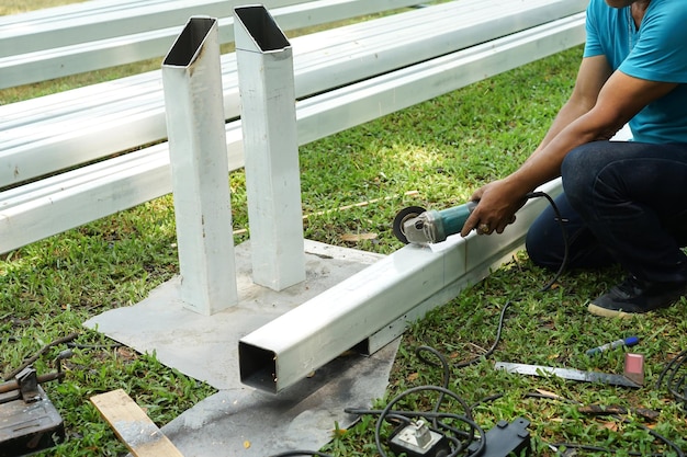 Asian smith worker are sawing the steel iron pole in the backyard garden at home