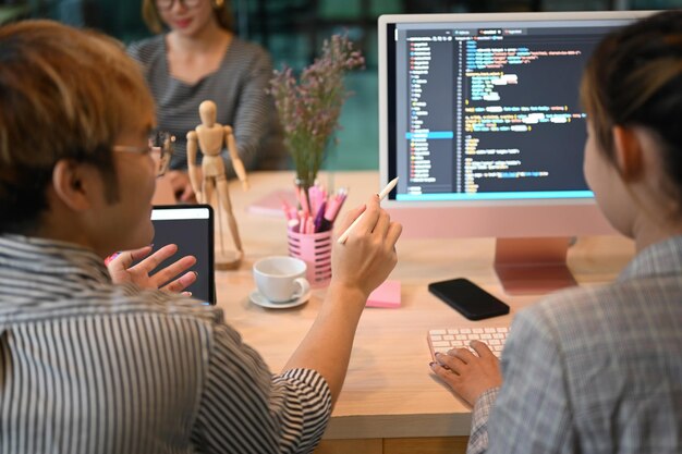 Asian software developers team brainstorming and programming on desktop computer in modern office