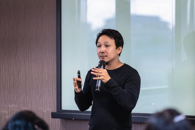 Asian Speaker or lecture with casual suit on the stage in front of the room presenting