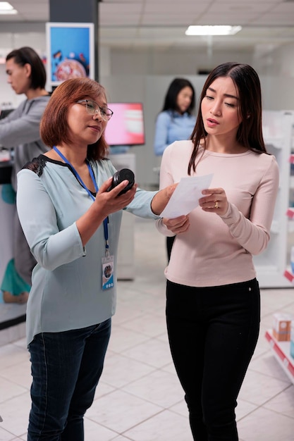 Asian specialist reading prescription paper in pharmacy shop to give medicaments and supplements to customer. Female client buying medication, drugs or capsules boxes from pharmaceutical drugstore.