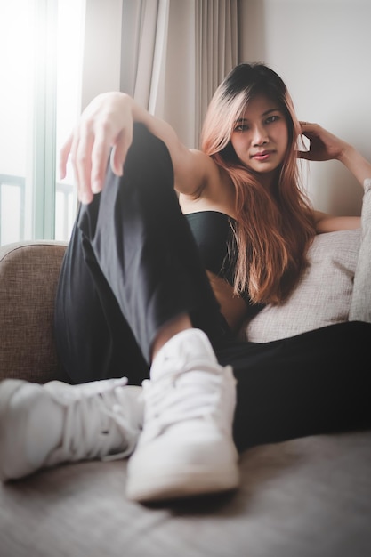 Asian sporty fashion model girl poseert met witte sneakers schoenen op sofa in een appartement voor coole street sport fashion