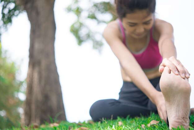 Asian sporty woman stretching arms breathing fresh air in the parkThailand people exercise concept