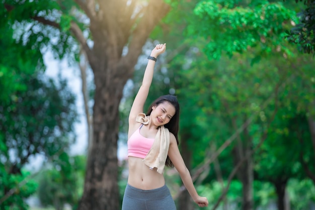 Asian sporty woman stretching arms breathing fresh air in the parkThailand people exercise concept
