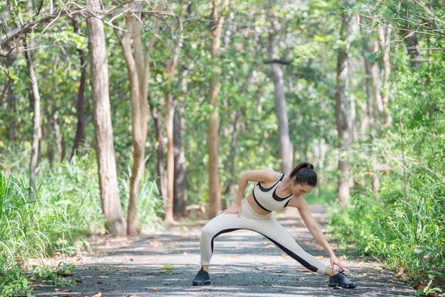 写真 公園で新鮮な空気を呼吸して体を伸ばすアジアのスポーティな女性タイの人々フィットネスと運動のコンセプト公園でのジョギング