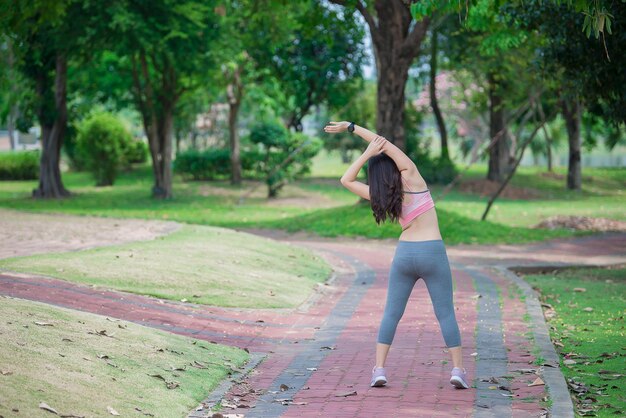 公園で新鮮な空気を呼吸して体を伸ばすアジアのスポーティな女性タイの人々フィットネスと運動の概念