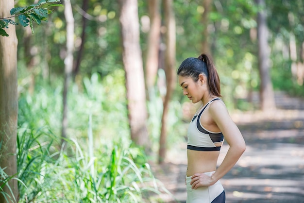 Asian sporty woman stretching body breathing fresh air in the parkThailand peopleFitness and exercise conceptJogging in the park