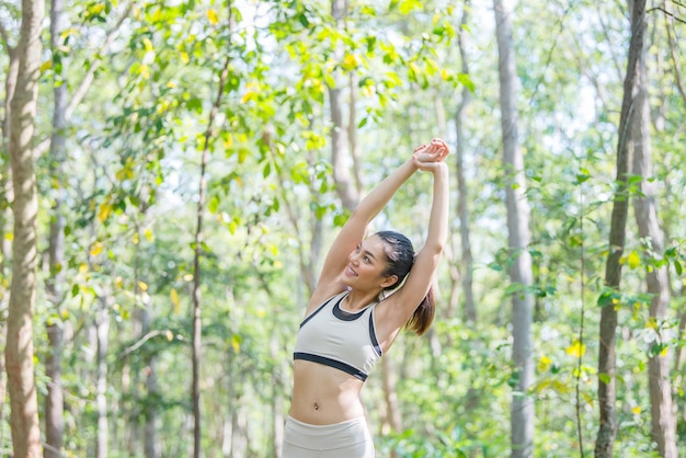公園で新鮮な空気を呼吸して体を伸ばすアジアのスポーティな女性タイの人々フィットネスと運動のコンセプト公園でのジョギング
