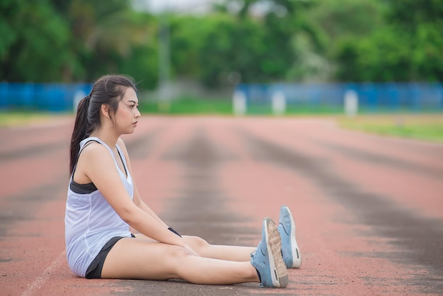 公園で新鮮な空気を呼吸して体を伸ばすアジアのスポーティな女性タイの人々フィットネスと運動のコンセプトトラックでのジョギング