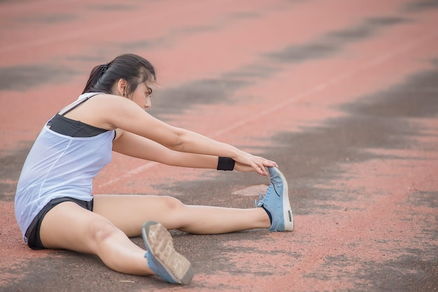 公園で新鮮な空気を呼吸して体を伸ばすアジアのスポーティな女性タイの人々フィットネスと運動のコンセプトトラックでのジョギング