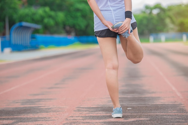 Donna sportiva asiatica che allunga il corpo respirando aria fresca nel parco persone della thailandia concetto di fitness ed esercizio jogging in pista