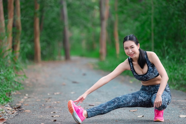 公園で体を伸ばすアジアのスポーティな女性タイの人々