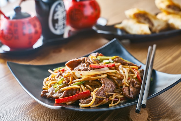 Foto tagliatelle fritte stir asiatiche con peperoni e cipolle di manzo