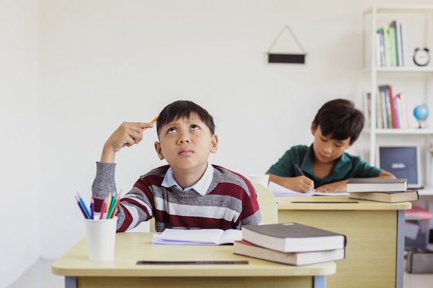 教室で試験中に考えるアジアの学生少年