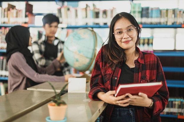 Asian student girl visiting public library for work on study research project holding notebook