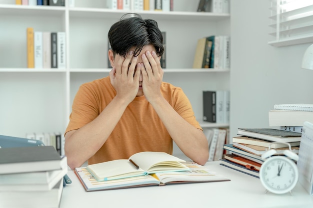 写真 アジアの学生男性は試験のために不安を抱えている男性はテストの準備をし、図書館でレッスンを学ぶストレス絶望急いで誤解読書を落胆させる期待知識疲れ