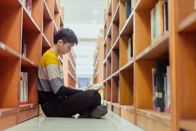 Photo asian student reads book in the library, lessons for exams, educational concepts