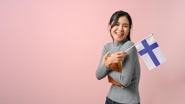 Asian student showing Finland flag on pink isolated background education concept