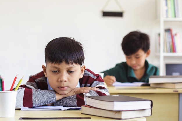 Asian student sitting daydreaming during a lesson in a classroom