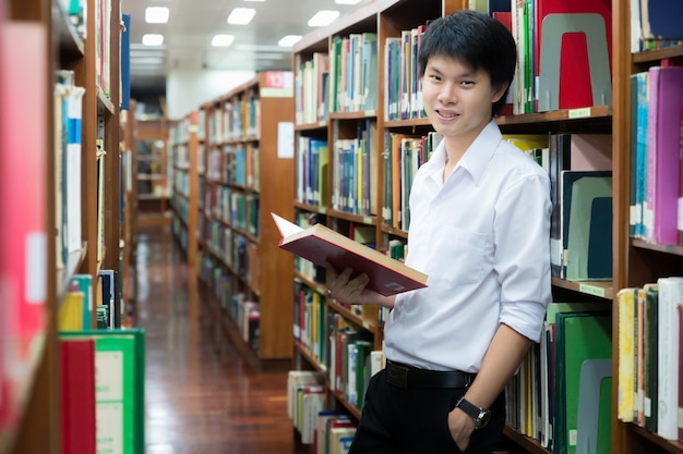 Studente asiatico in lettura uniforme in biblioteca