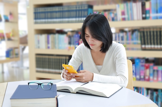 アジアの学生が図書館でスマートフォンを使う