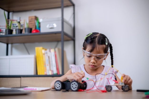 アジアの学生は、STEM STEAM でロボットカーと電子基板ケーブルをコーディングすることで自宅で学習します 数学 工学 科学技術 コンピュータコード ロボット工学で子供の概念