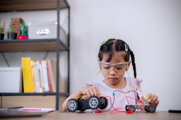 アジアの学生は、STEM STEAM でロボットカーと電子基板ケーブルをコーディングすることで自宅で学習します 数学 工学 科学技術 コンピュータコード ロボット工学で子供の概念