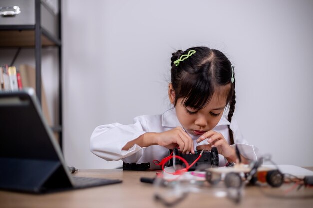 Asian students learn at home by coding robot cars and electronic board cables in STEM STEAM mathematics engineering science technology computer code in robotics for kids' concepts