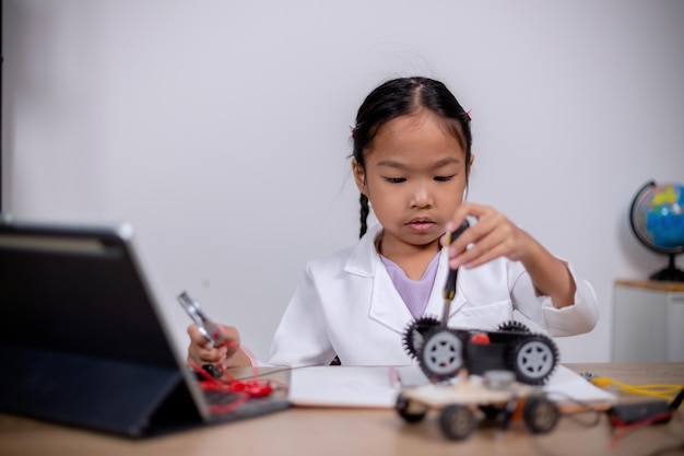 アジアの学生は、STEM STEAM でロボットカーと電子基板ケーブルをコーディングすることで自宅で学習します 数学 工学 科学技術 コンピュータコード ロボット工学で子供の概念