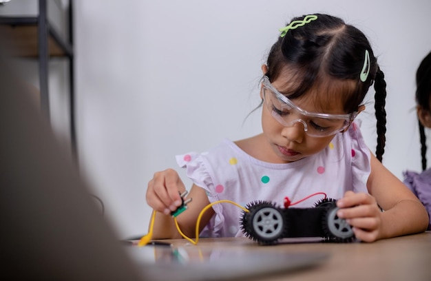 アジアの学生は、STEM STEAM でロボットカーと電子基板ケーブルをコーディングすることで自宅で学習します 数学 工学 科学技術 コンピュータコード ロボット工学で子供の概念