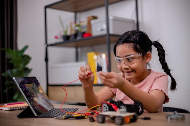 Asian students learn at home by coding robot cars and electronic board cables in STEM STEAM mathematics engineering science technology computer code in robotics for kids' concepts