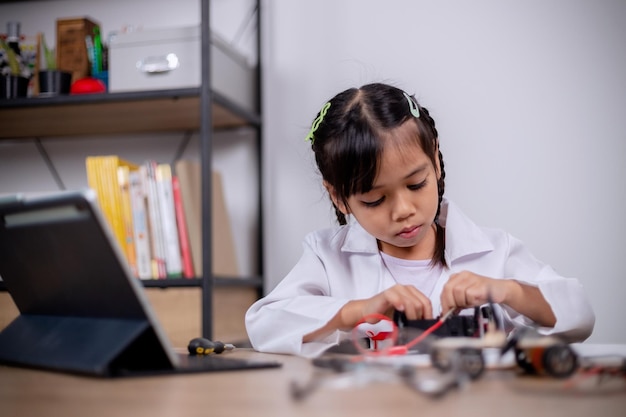 Asian students learn at home by coding robot cars and electronic board cables in STEM STEAM mathematics engineering science technology computer code in robotics for kids' concepts