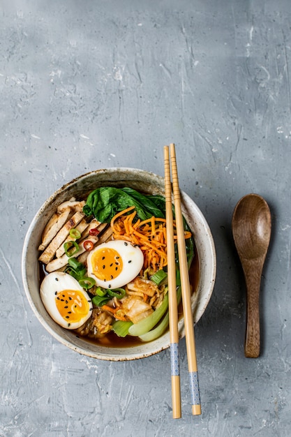 Asian style ramen noodle soup with bok choy, carrot, lime, sesame seeds, chicken and egg