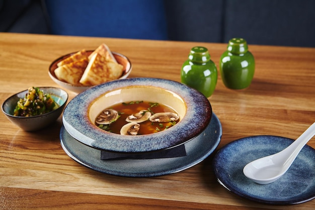 Asian style soup with mushrooms miso soup in bowl on wooden table