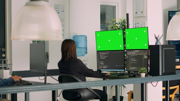 ソフトウェアイノベーションオフィスの複数のモニターでhtmlスクリプトコードとグリーンスクリーンを使用するアジアのシステムエンジニア。ターミナル ウィンドウと独立したクロマキー ディスプレイを操作するプログラマー。三脚撮影。