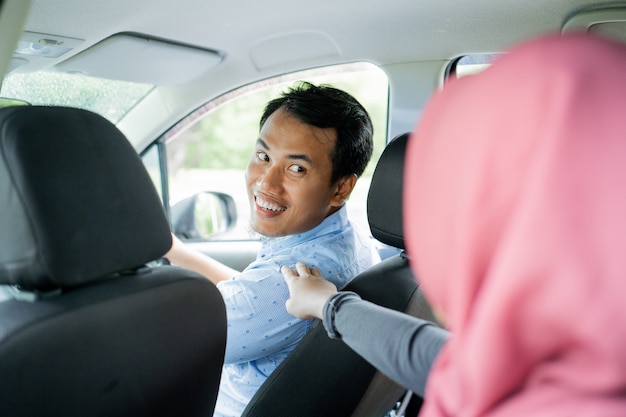 Asian taxi driver looking back after touch by hijab passenger