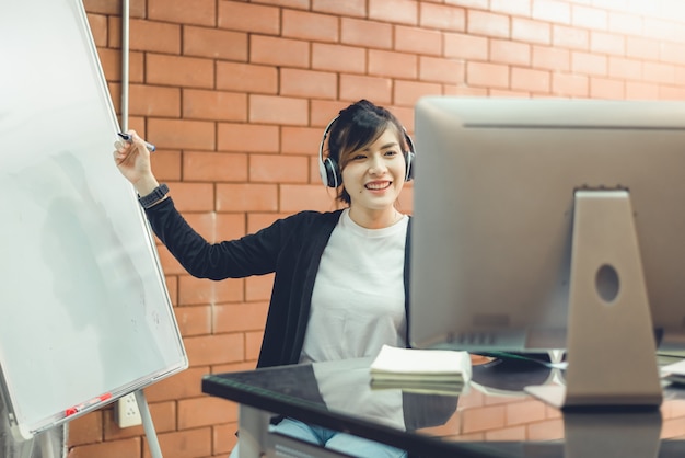 Un insegnante asiatico spiega gli esercizi alla lavagna agli studenti che studiano online.