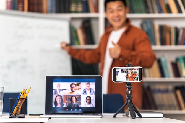 Asian Teacher Man Teaching Talking To Laptop And Smartphone Indoor