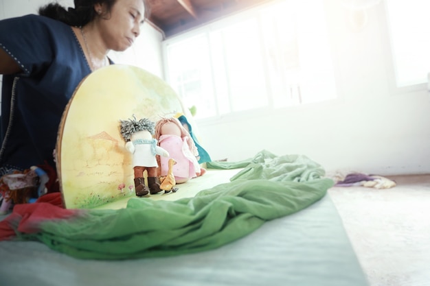 Asian  teacher telling story with hand made Waldorf dolls.