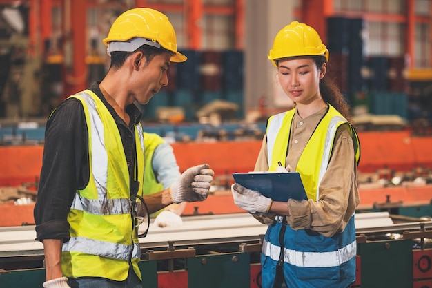 I dipendenti del team asiatico che lavorano in fabbrica il gruppo di ingegneri asiatici controlla la produzione in fabbrica industriale