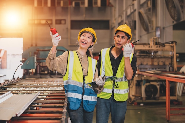 I dipendenti del team asiatico che lavorano in fabbrica il gruppo di ingegneri asiatici controlla la produzione in fabbrica industriale