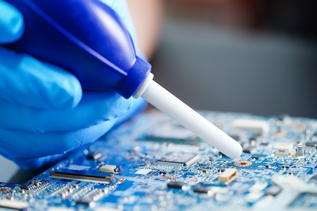 Asian Technician cleaning dirty dust circuit main board computer with cleaning rubber ball.