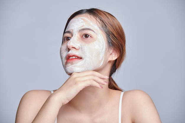 Asian teen girl in moisturizing has clay mask on face enjoys softness Asia woman beauty skin care