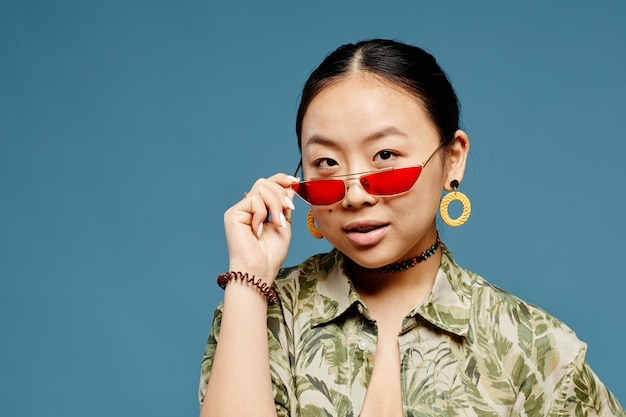 Asian Teenage Girl Wearing Sunglasses over Blue