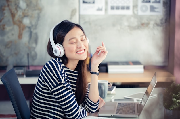 Asian teenage girls are happily listening to music from headphones