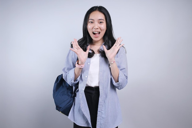 Азиатская студентка-подросток с рюкзаком показывает шокированное выражение удивления