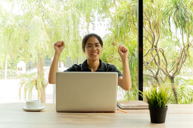 Adolescente asiatico eccitato che celebra successo davanti al netbook.