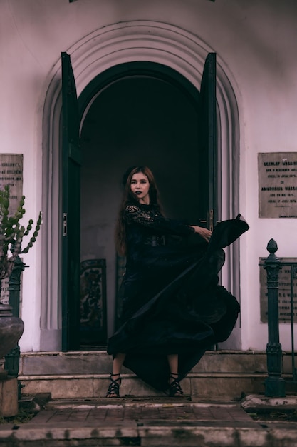 Foto un'adolescente asiatica che posa nel suo vestito nero che fluttua nell'aria mentre si trova di fronte al cimitero