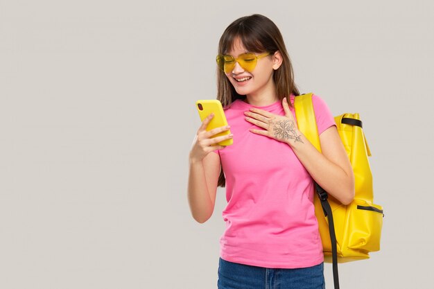 An Asian teenager woman in heart-shaped glasses holds a mobile phone in hands. New Gadget Advertising